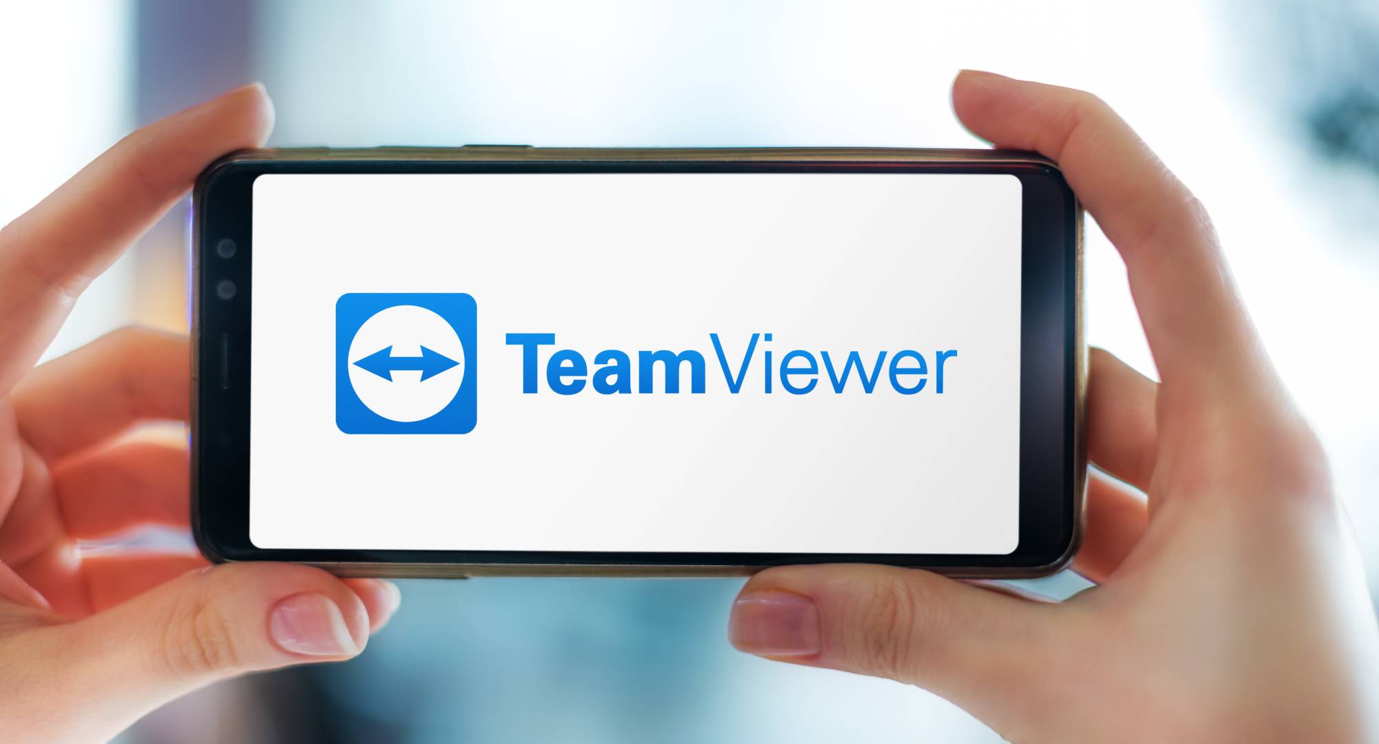 Bild på person som håller i sin mobiltelefon med Team Viewer. LogSoft använder Team Viewer för att utförda utbildningar, support samt demo till kunder som önskar få detta.